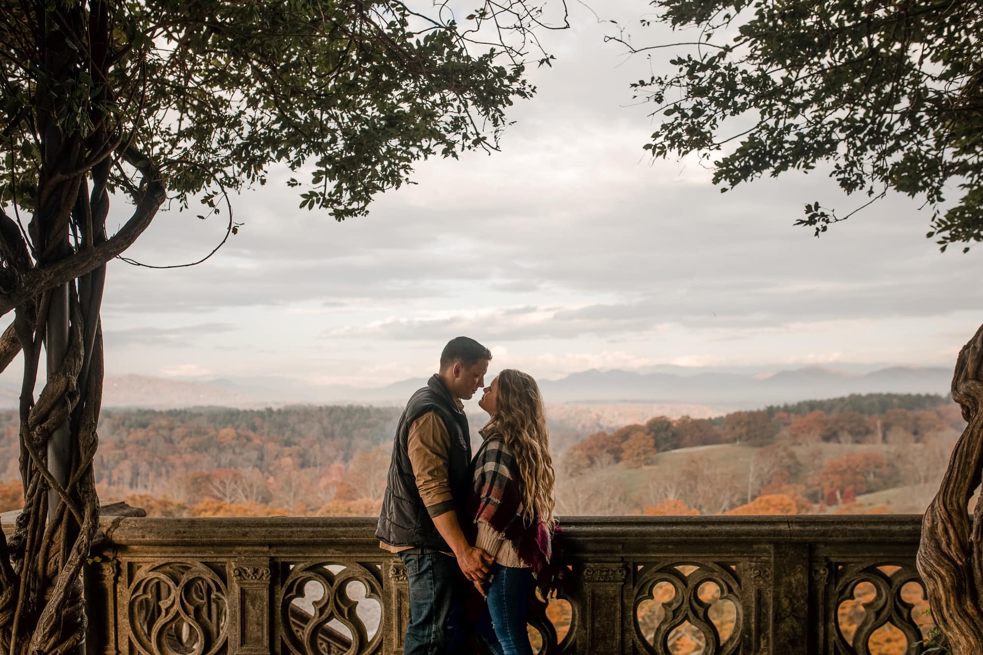 Couple kissing on bridge overlooking autumn trees at Biltmore Estate North Carolina photography done by Kathy Beaver.