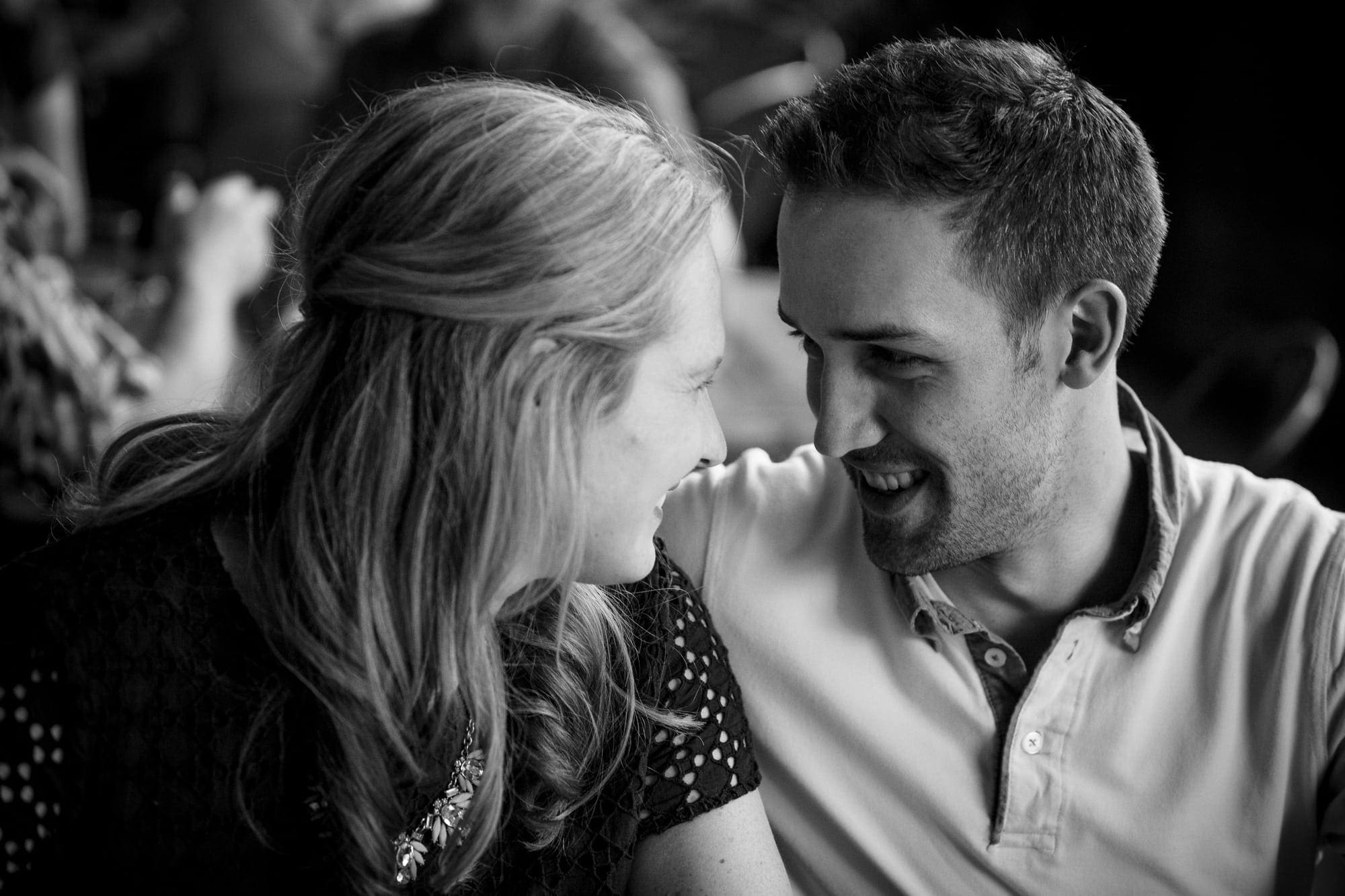 Black and white photo of couple affectionately smiling at one another in restaurant in Downtown Asheville North Carolina photography done by Kathy Beaver.