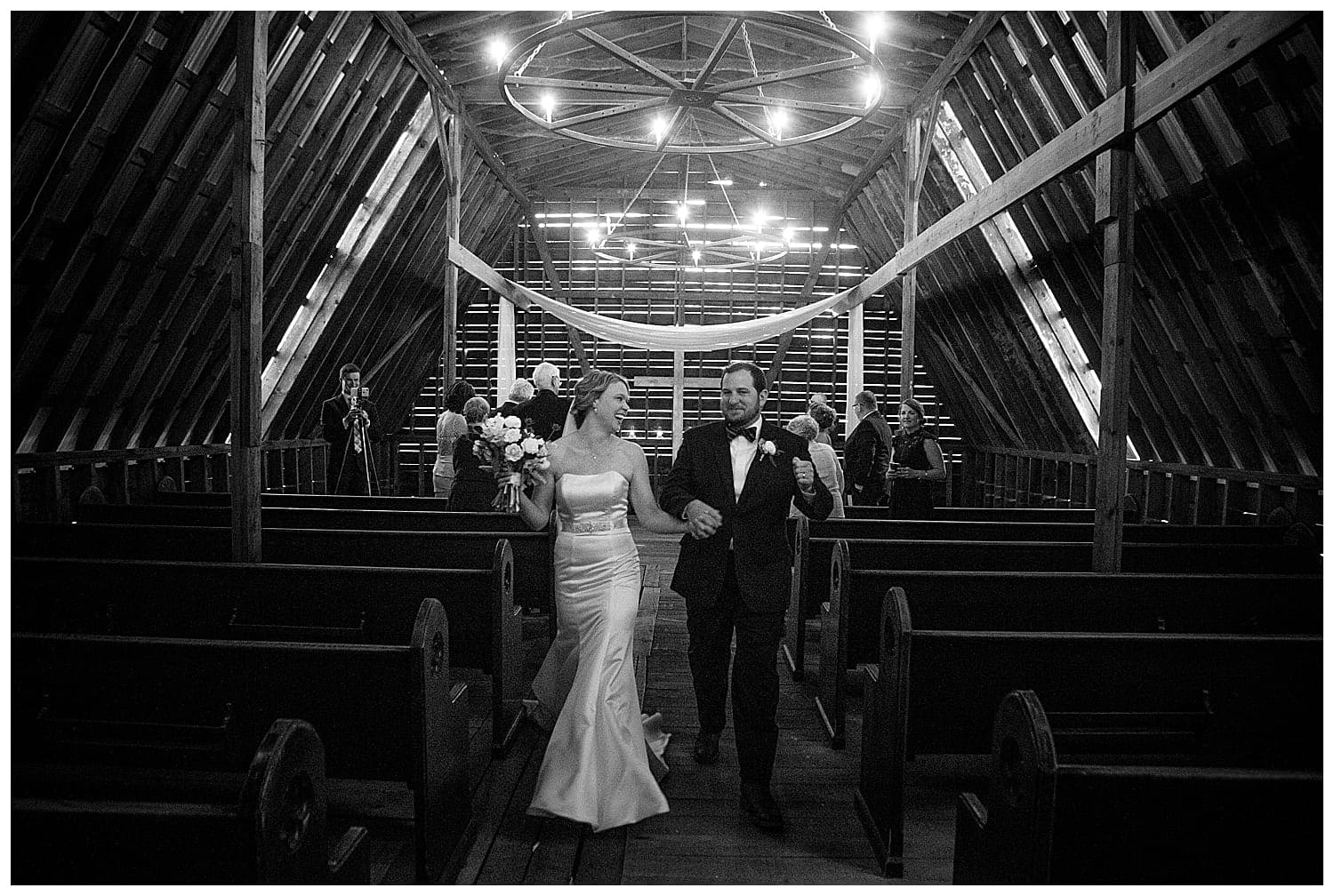 Black and white photos of newlywed couple walking down the aisle of a wooden chapel smiling and laughing with one another after saying I do