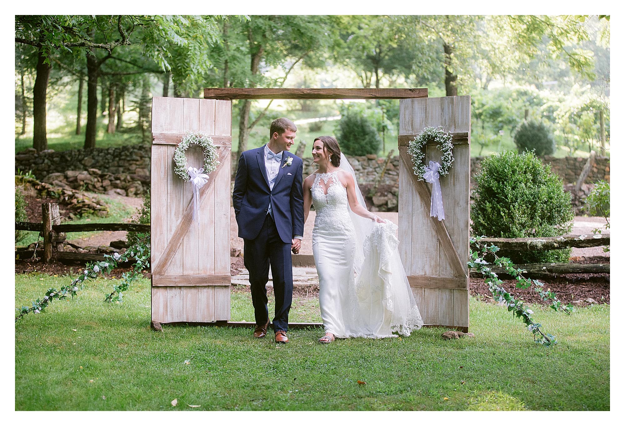 Bride and groom holding hangs walking through decorated wooden doors outside