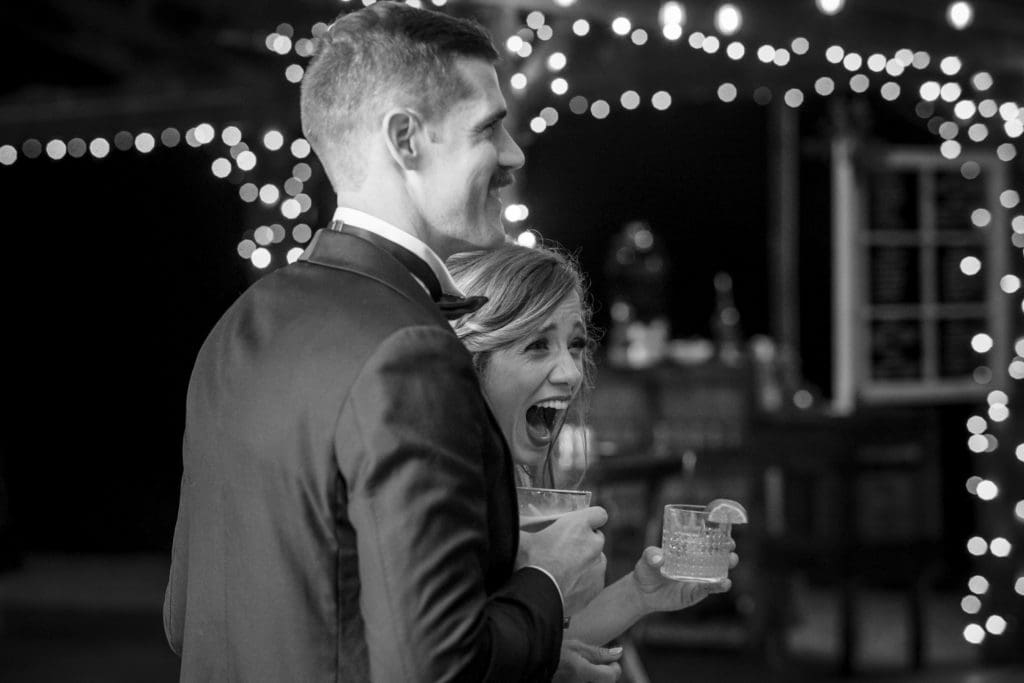 Black and white photo of the bride and groom laughing during toasts | Kathy Beaver Photography | Asheville Wedding Photographer