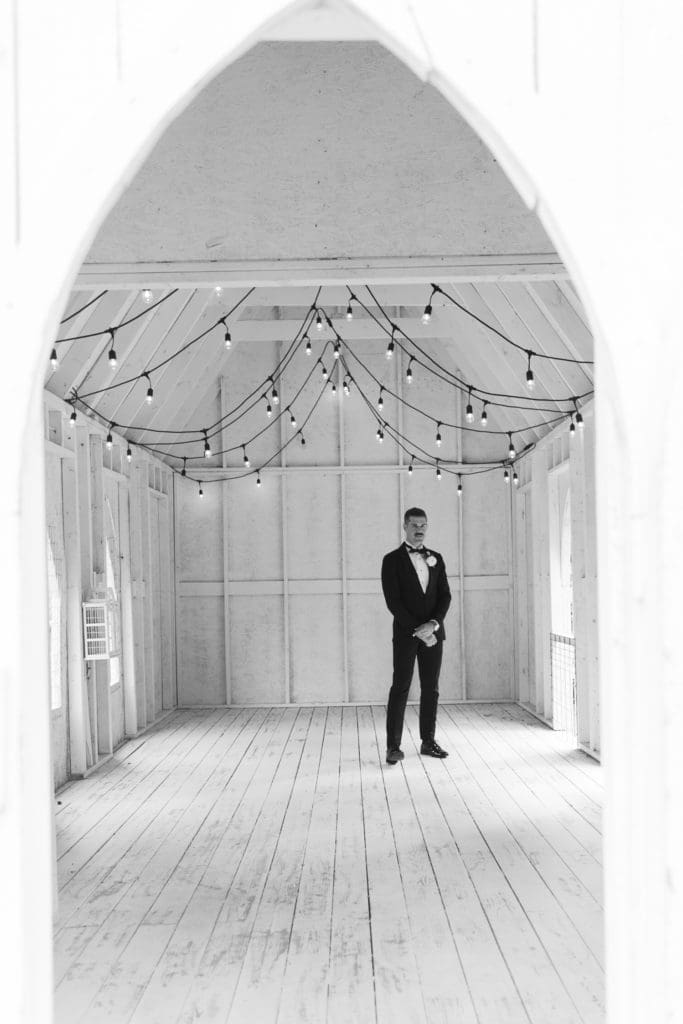 Black and white photo of the groom inside the coop at The Farm | Kathy Beaver Photography | Asheville Wedding Photographer