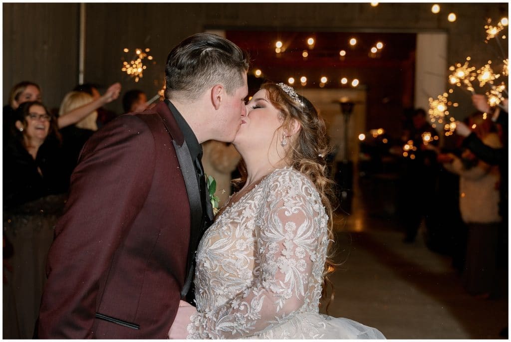 The bride and groom share a kiss during their sparkler exit | Asheville Wedding Photographer
