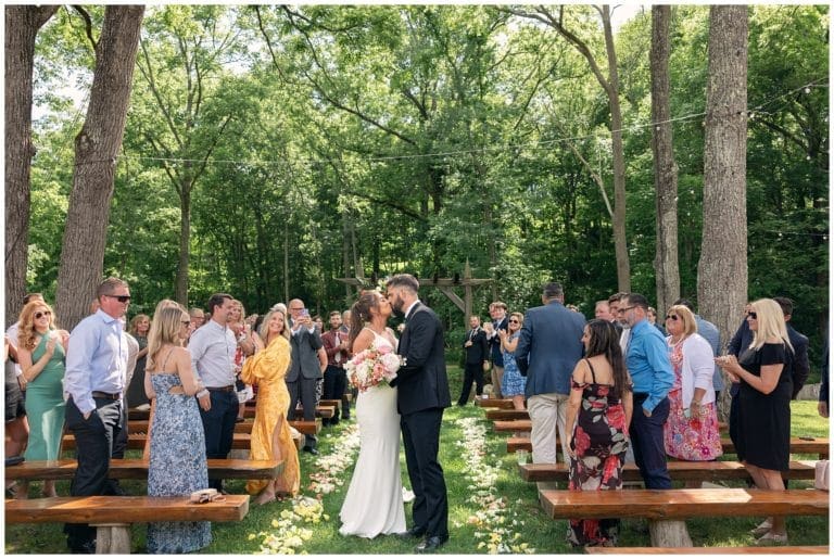 Bride and groom kiss at end of the aisle