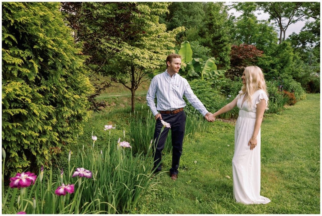 Engaged couple stands hand in hand in field of day lilies - Ideas for your Asheville Engagement Session