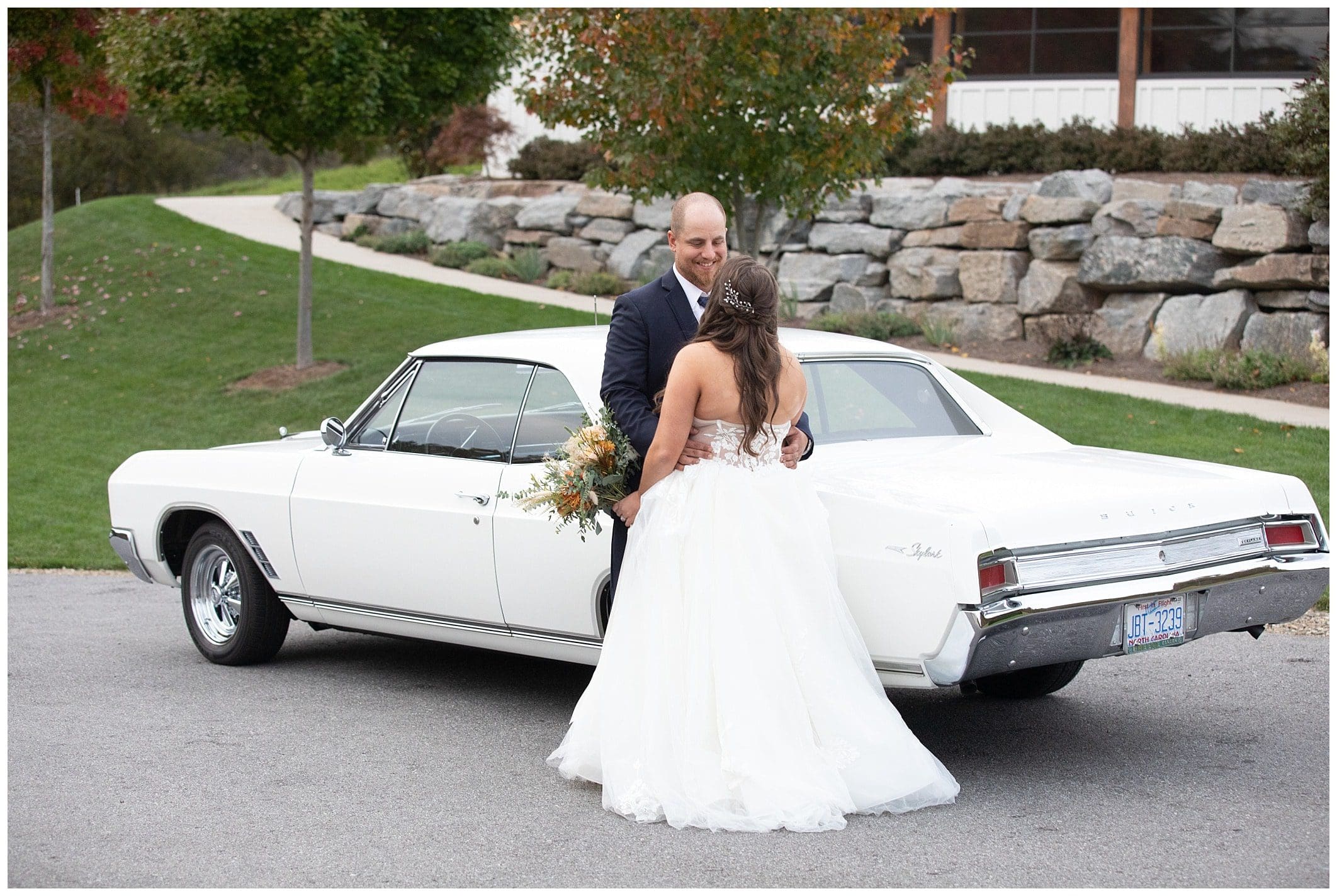bride and groom poses in front of classic white car