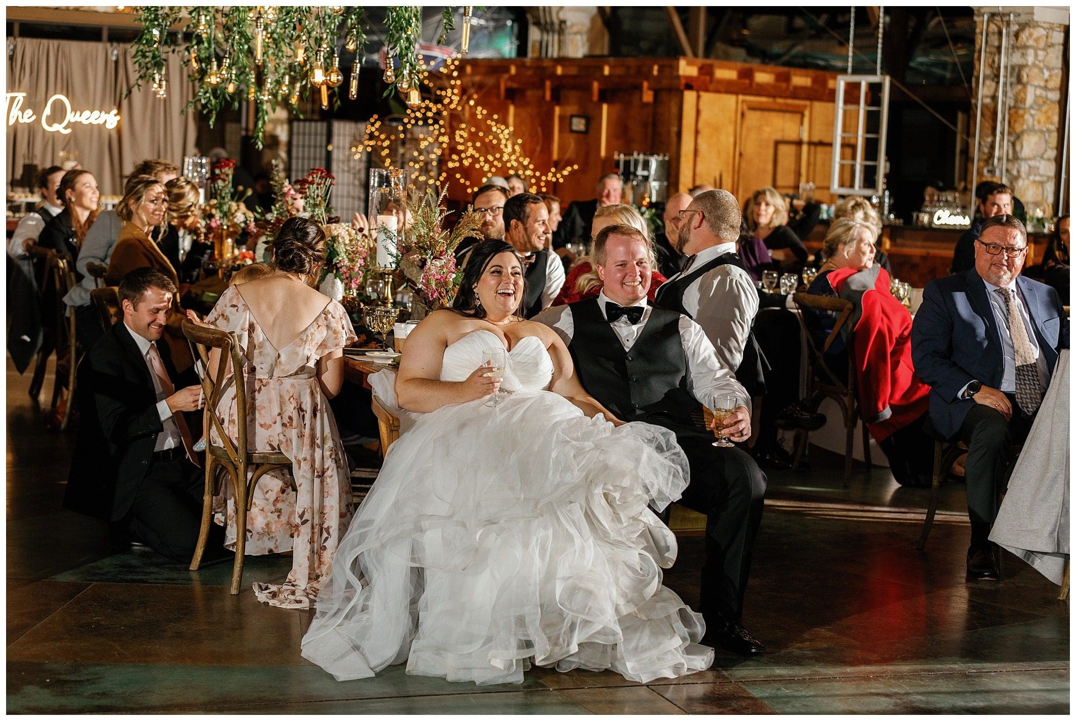 bride and groom sitting and laughing at their reception