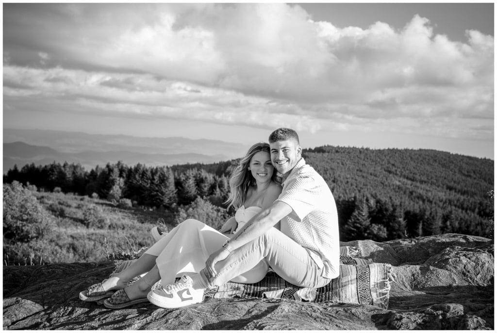 A black and white photo of a couple sitting on top of a mountain at theirEngagement session at Black Balsam & Graveyard Fields