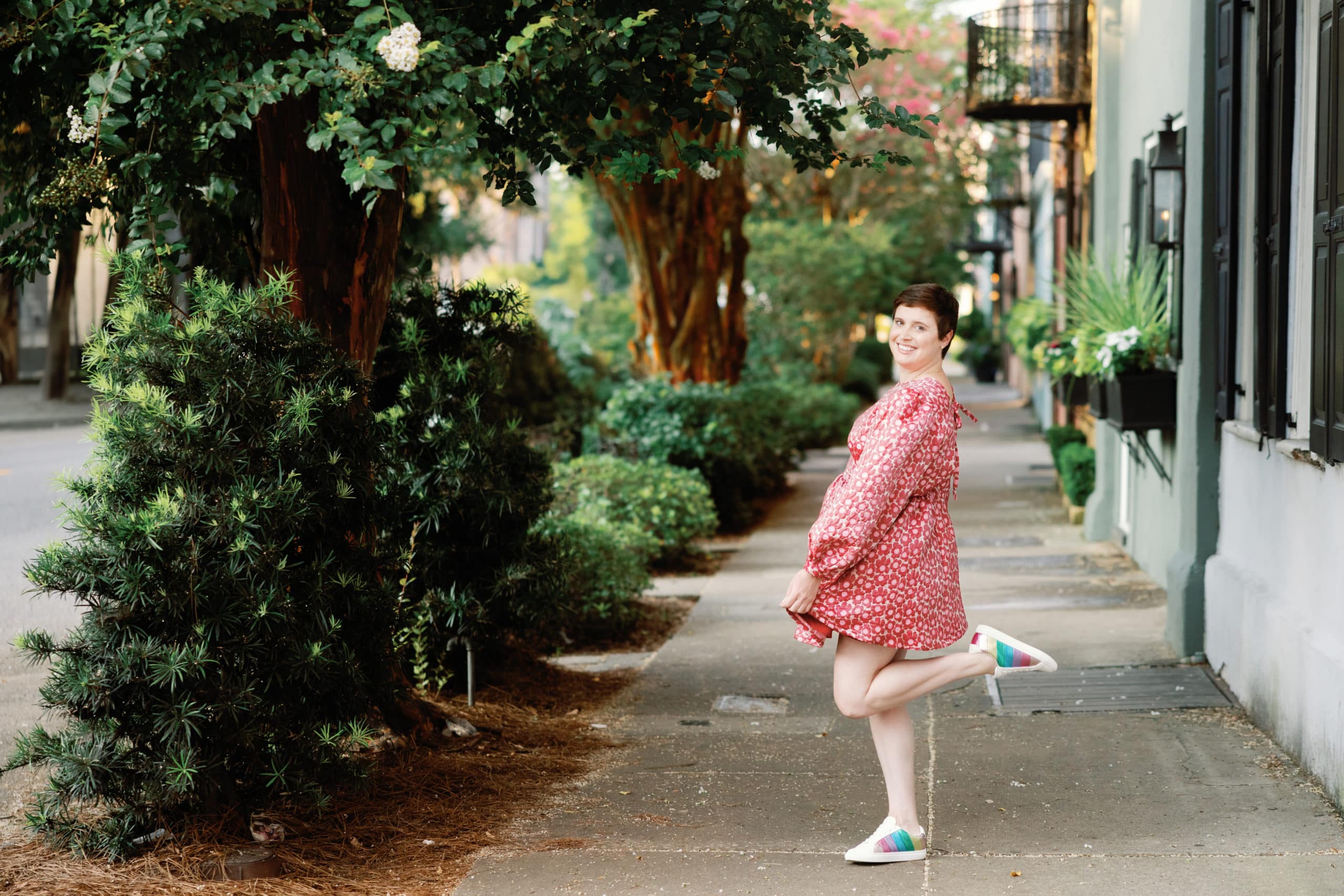 A woman in a pink dress standing on a Charleston sidewalk during the Content Creation Retreat.