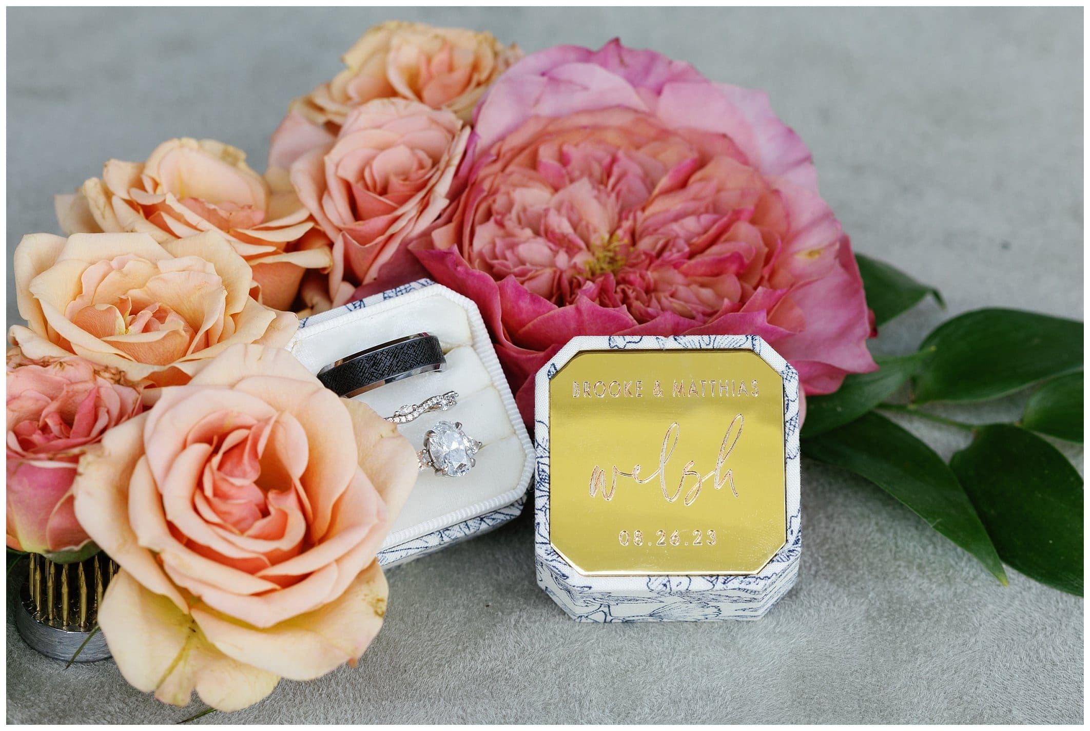 A wedding ring box with flowers and a wedding ring.