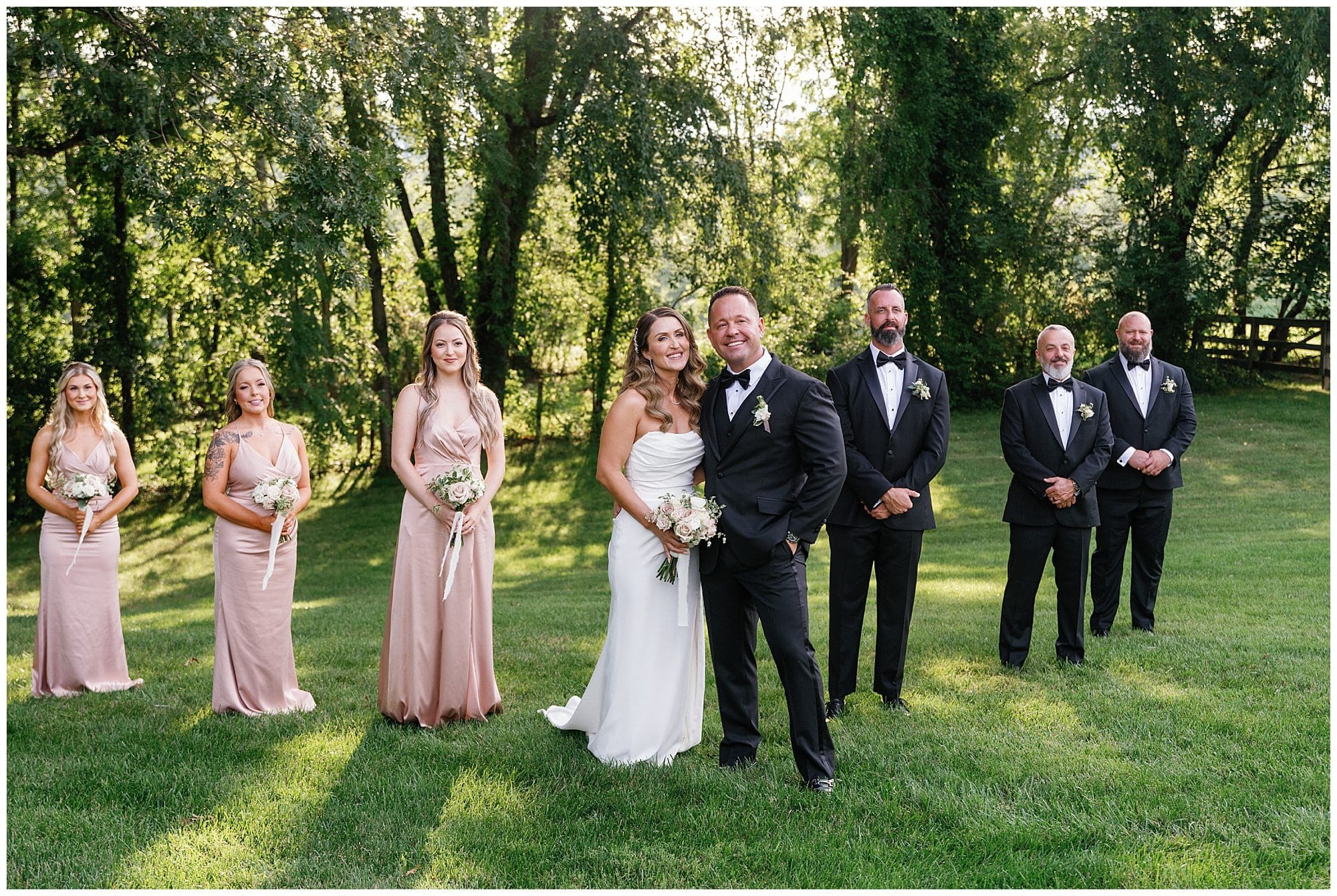 Wedding party in field with gorgeous sunlight behind them at this July wedding at the Farm 