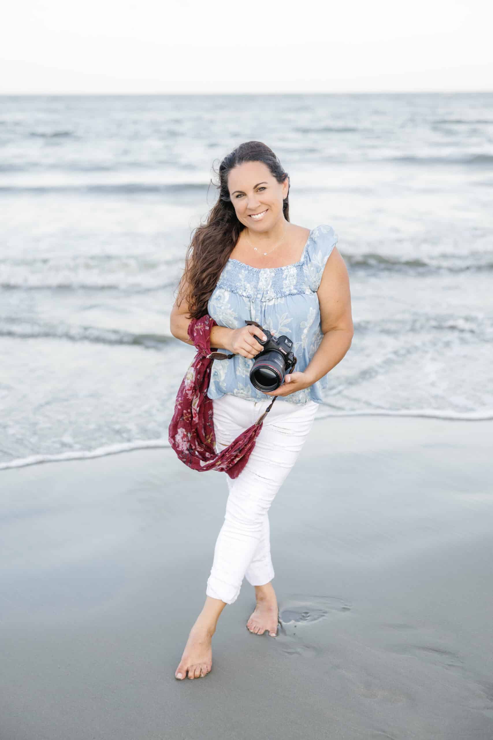 A woman participating in the 2024 Winter Content Creation Retreat captures moments with her camera on the beach.