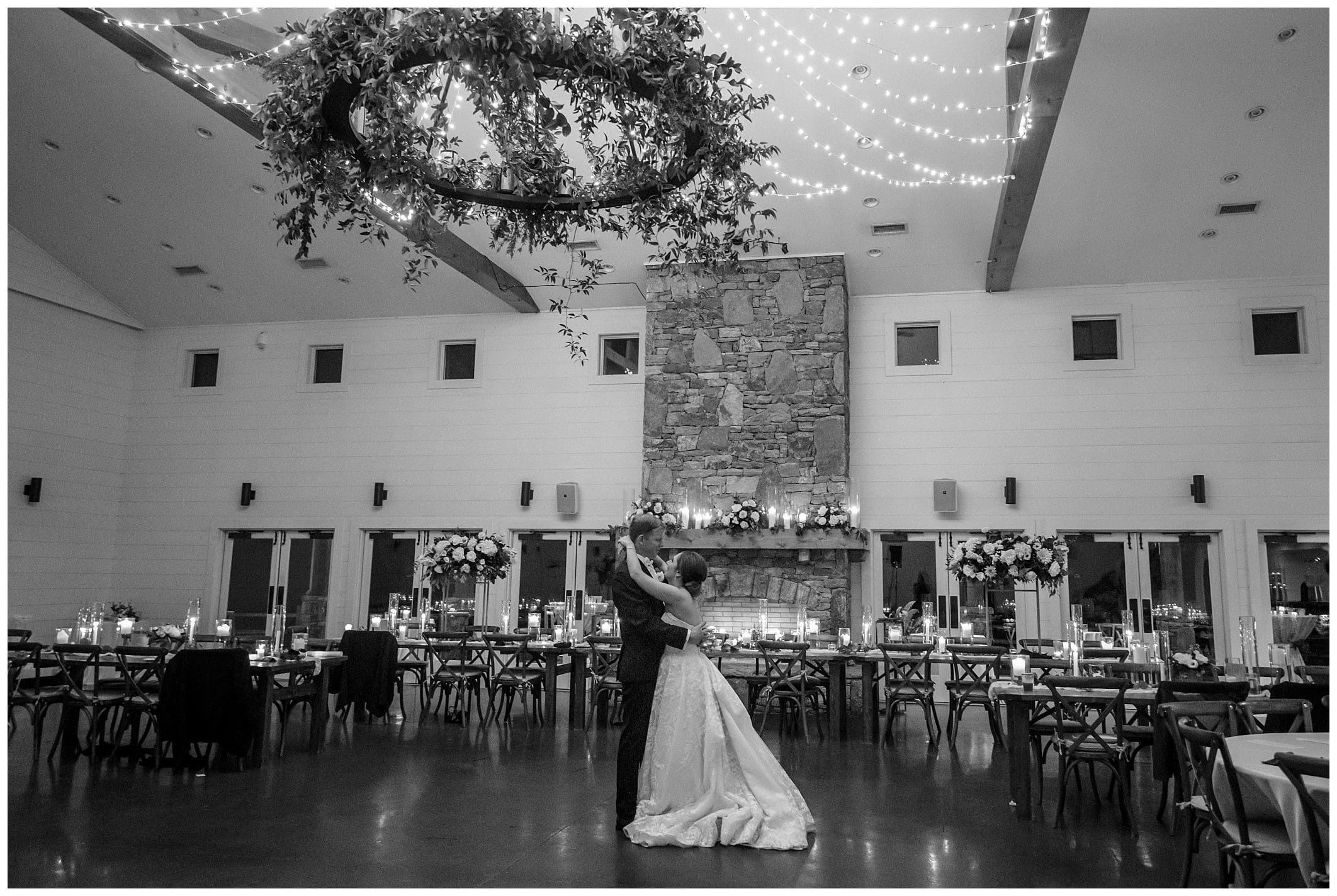 A black and white photo of a bride and groom dancing in a ballroom.