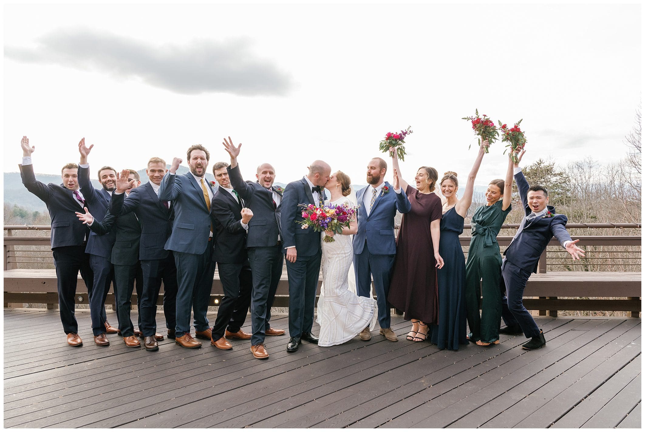 A group of bridesmaids and groomsmen pose for a photo on a deck.
