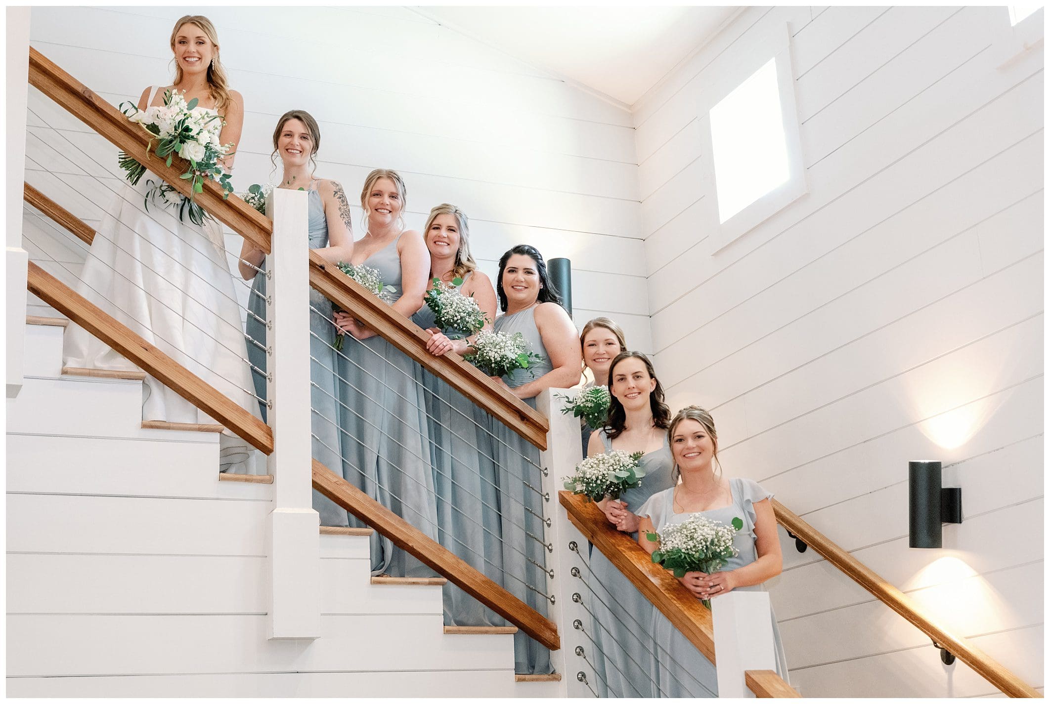 A bride and her bridesmaids pose on the stairs.