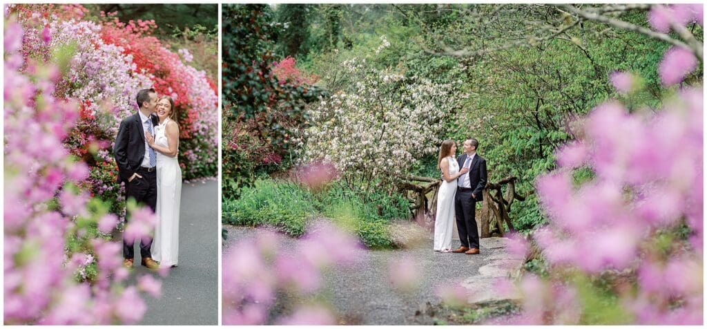 A couple embracing on a wooden bridge during their spring engagement session at Biltmore, surrounded by lush, blooming pink and white flowers, with a serene nature backdrop.