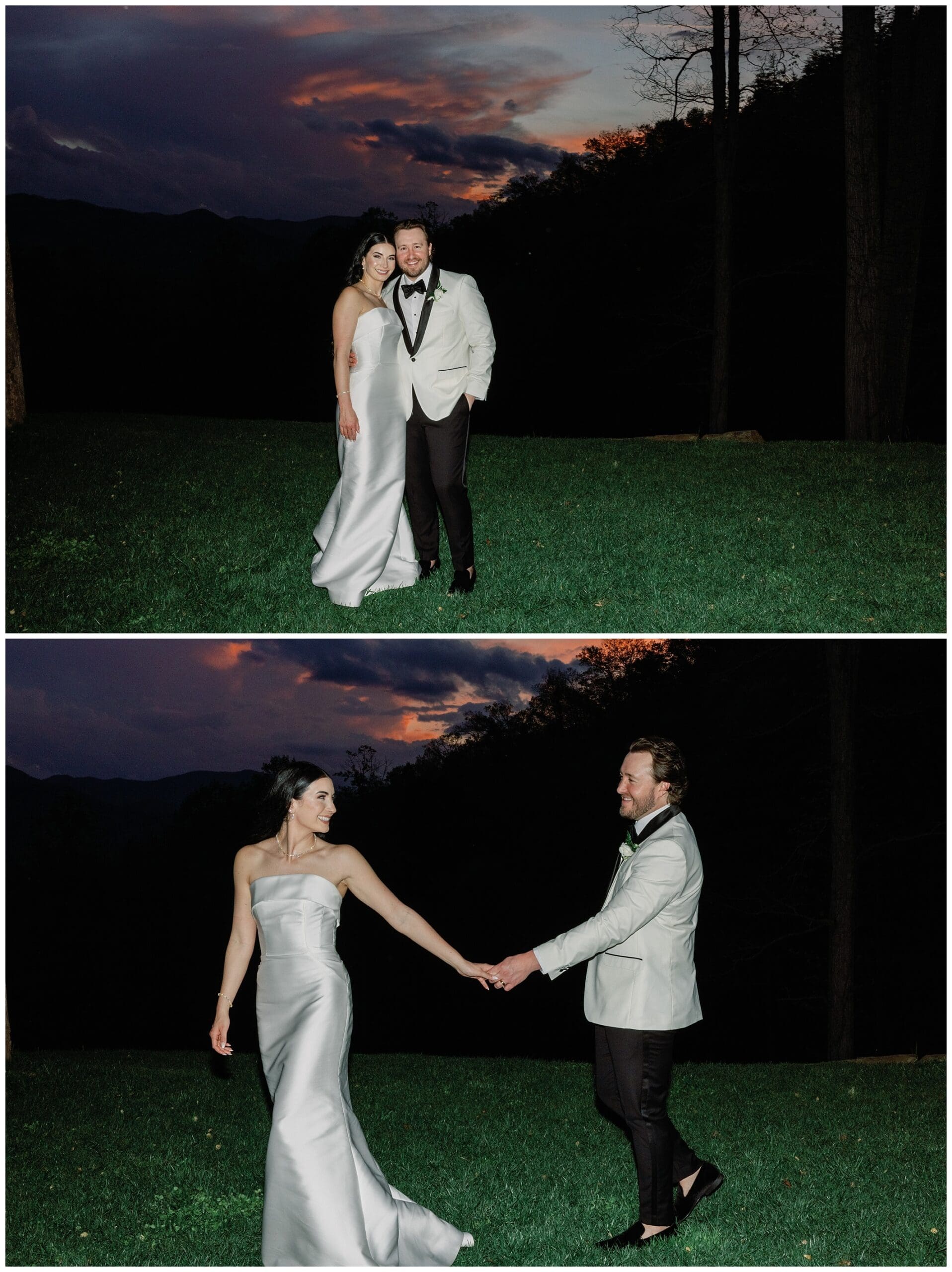 A bride in a white satin dress and a groom in a light gray suit stand holding hands outdoors at dusk, with a vibrant sunset and mountains in the background.