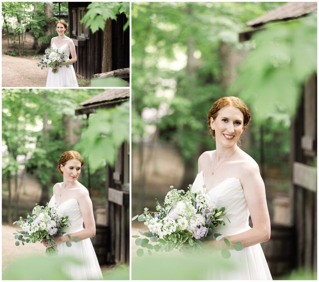 A bride in a white strapless wedding dress holds a bouquet of flowers while posing outdoors next to a rustic wooden building.