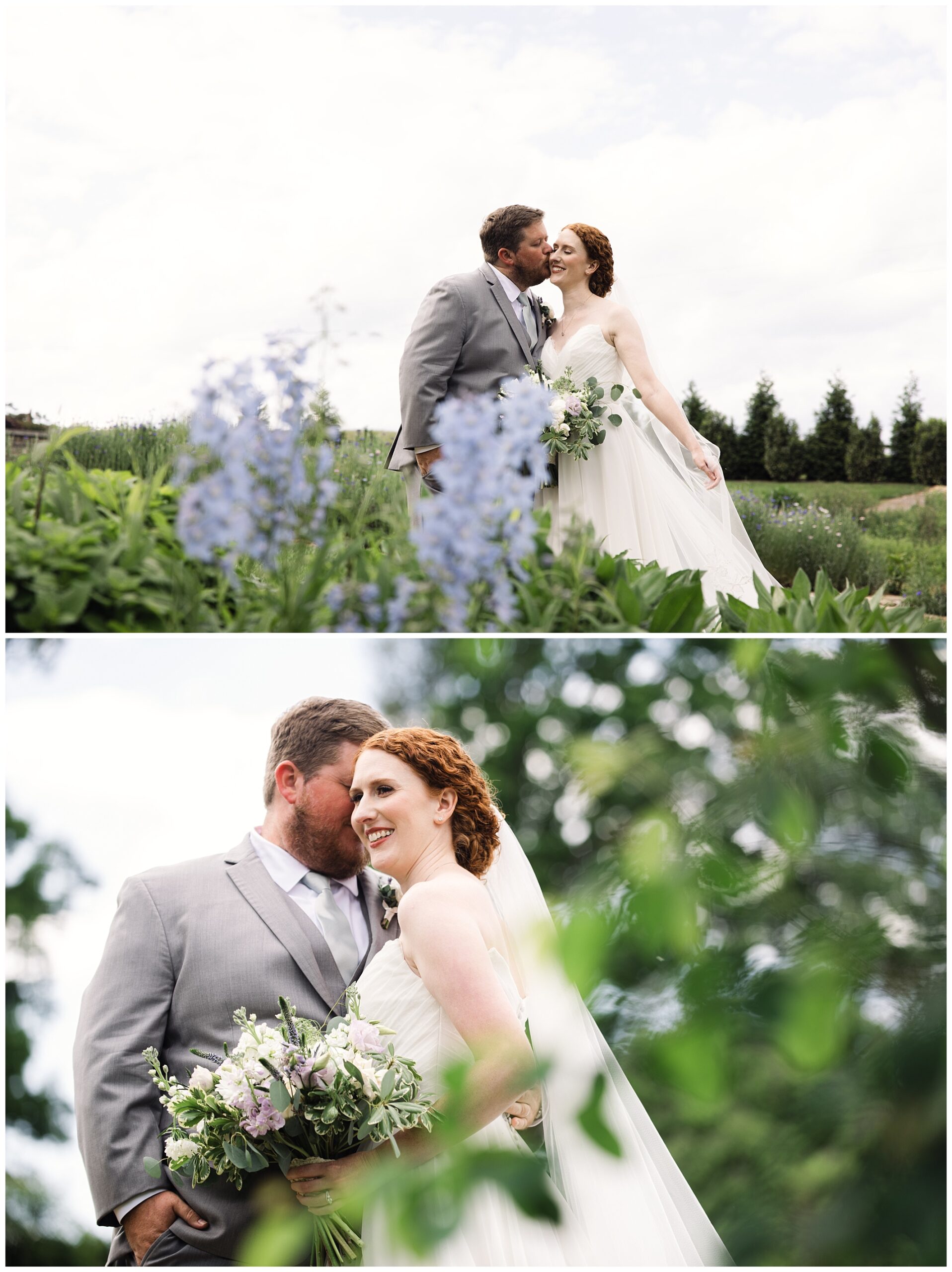 A couple in wedding attire stands in a garden with flowers and greenery. The man is in a gray suit, the woman in a white dress, holding a bouquet. They share an affectionate moment and smile while posing.