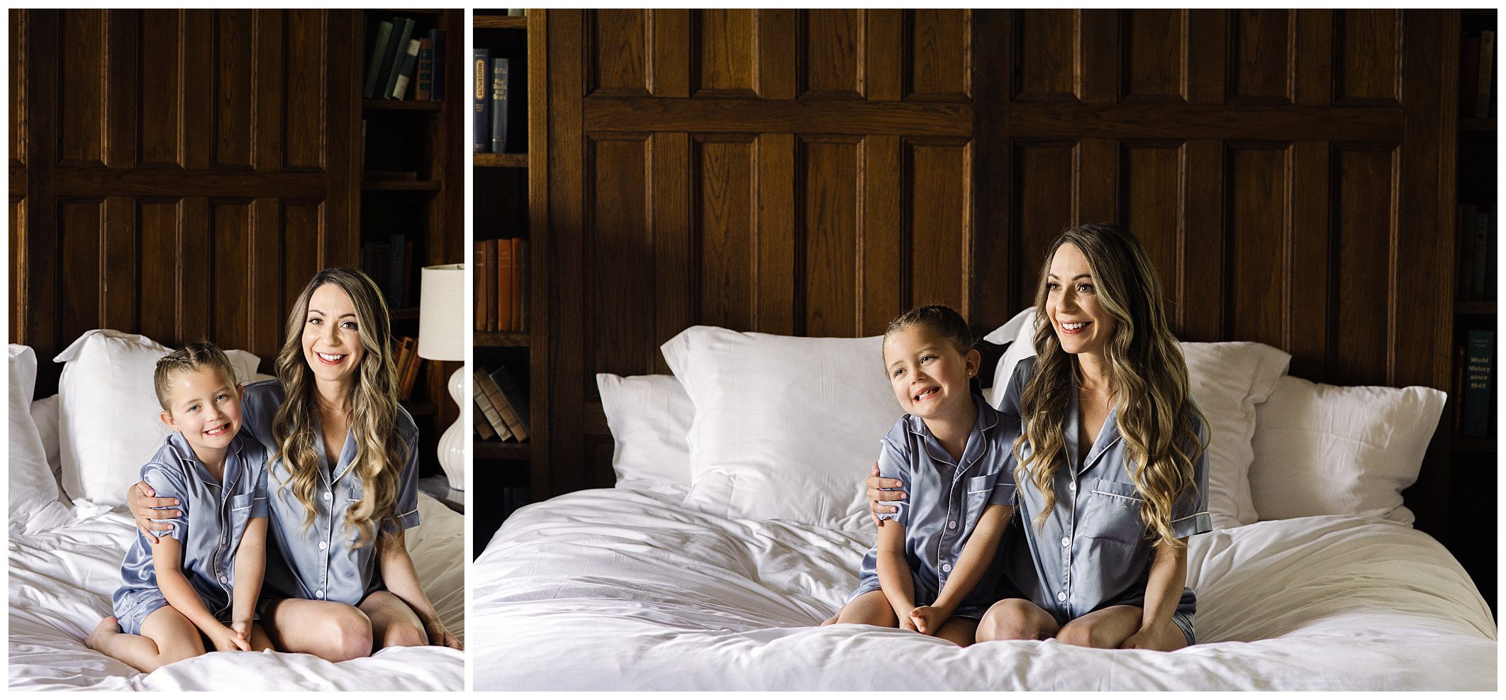 A woman and a child, both wearing blue pajamas, sitting and smiling on a white bed with a wooden headboard in the background.