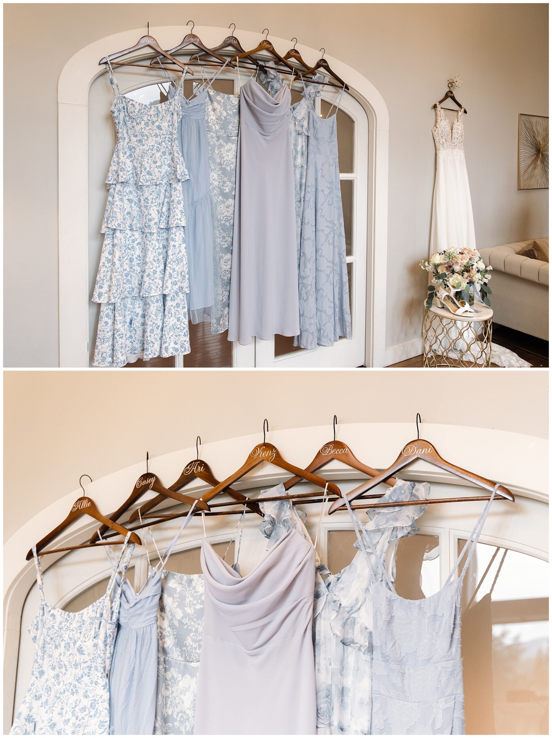 Several light blue and gray dresses are hanging on wooden hangers in front of a white arched doorway. A white dress is displayed separately on the right side near a small table with a floral arrangement.