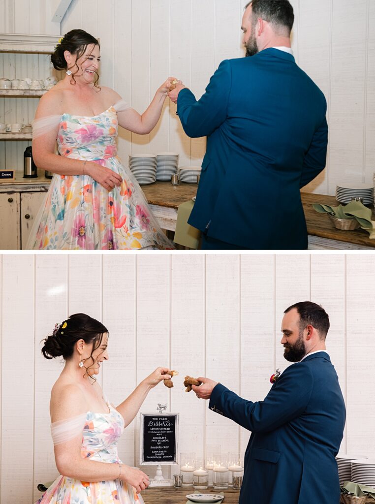 A woman in a floral dress and a man in a blue suit clink pastries together in a kitchen, capturing the sweet spirit of an Asheville NC spring garden wedding.