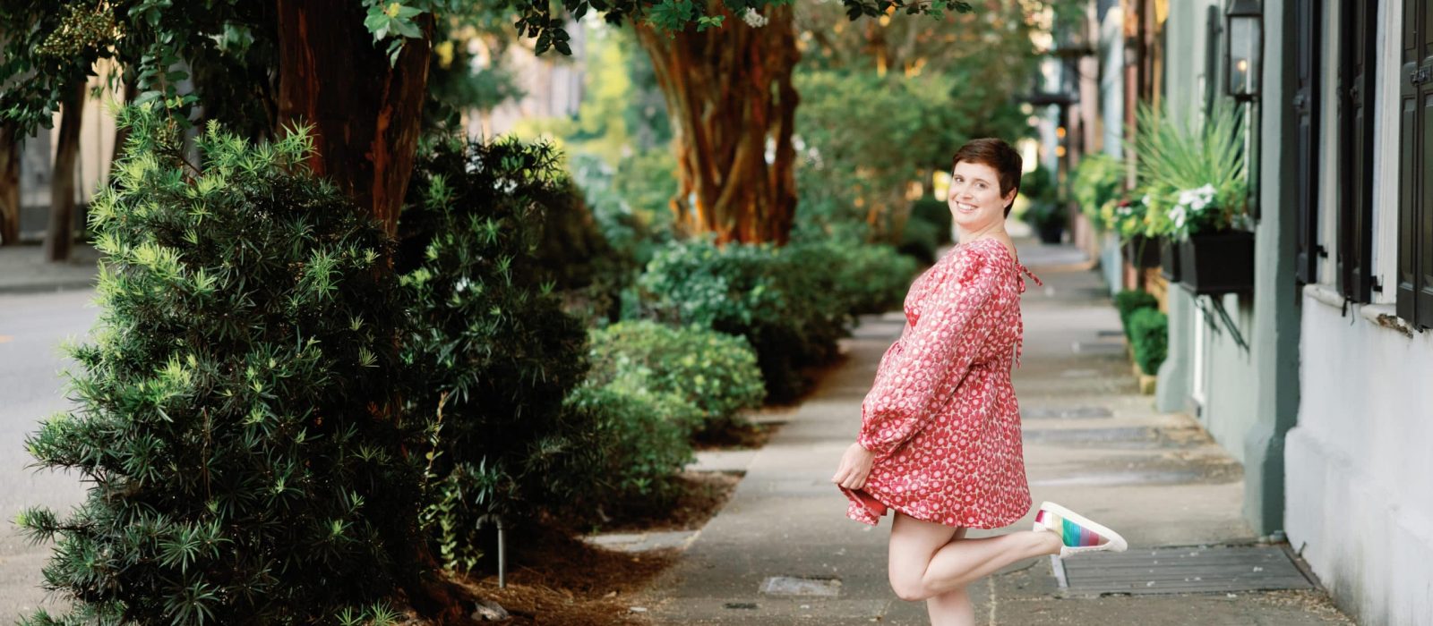 A woman in a pink dress standing on a Charleston sidewalk during the Content Creation Retreat.