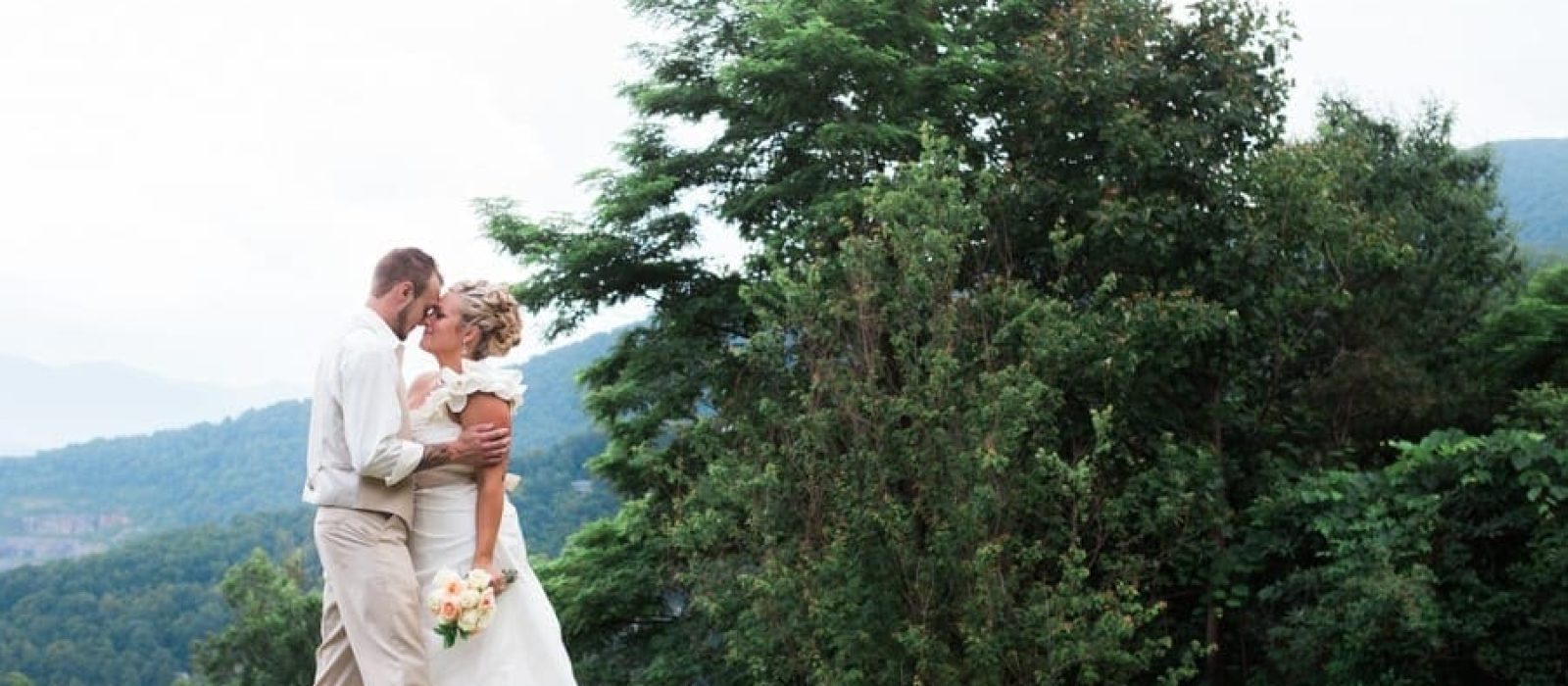 Bride and groom kiss with mountain view behind them