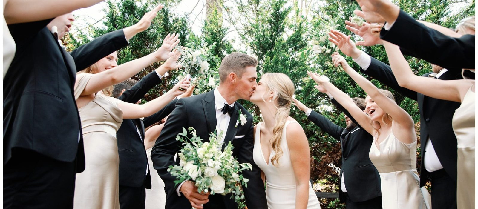 A fall wedding party at Crest Center joyously raises their hands in the air.