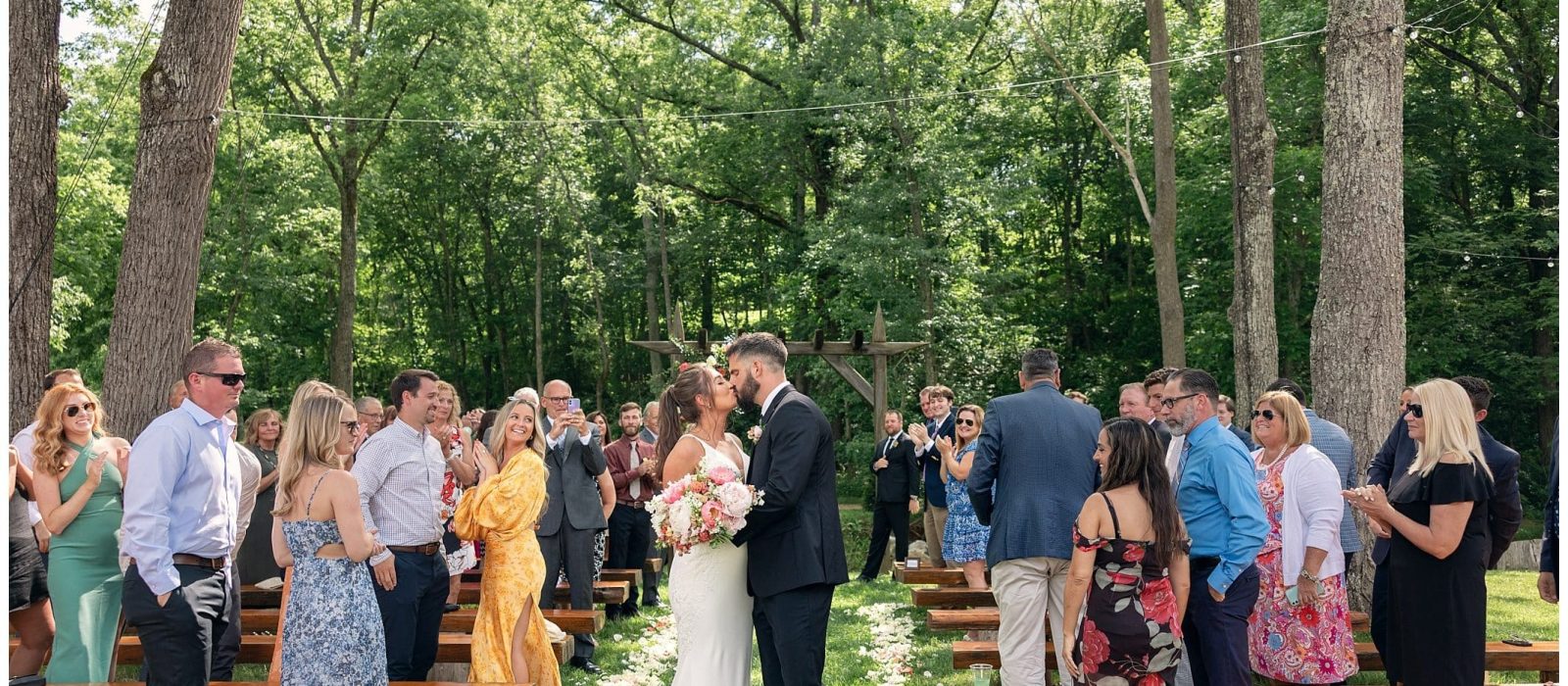 Bride and groom kiss at end of the aisle